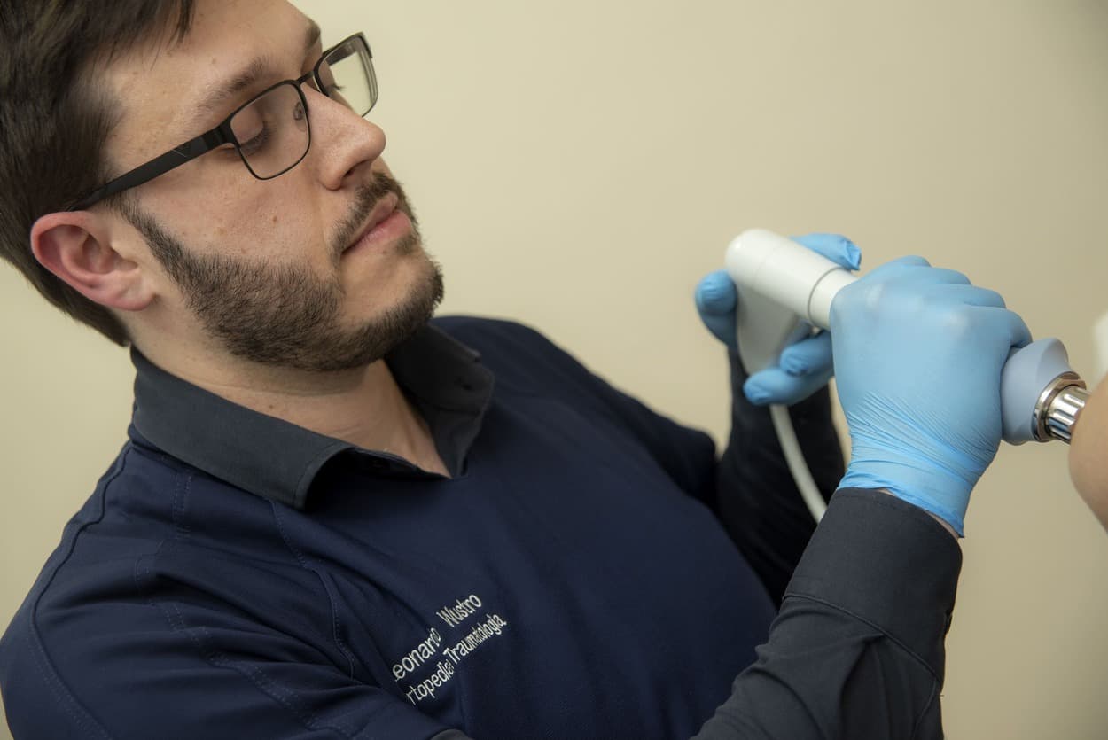 Dr. Leonardo Wustro aplicando ondas de choque em paciente no consultório